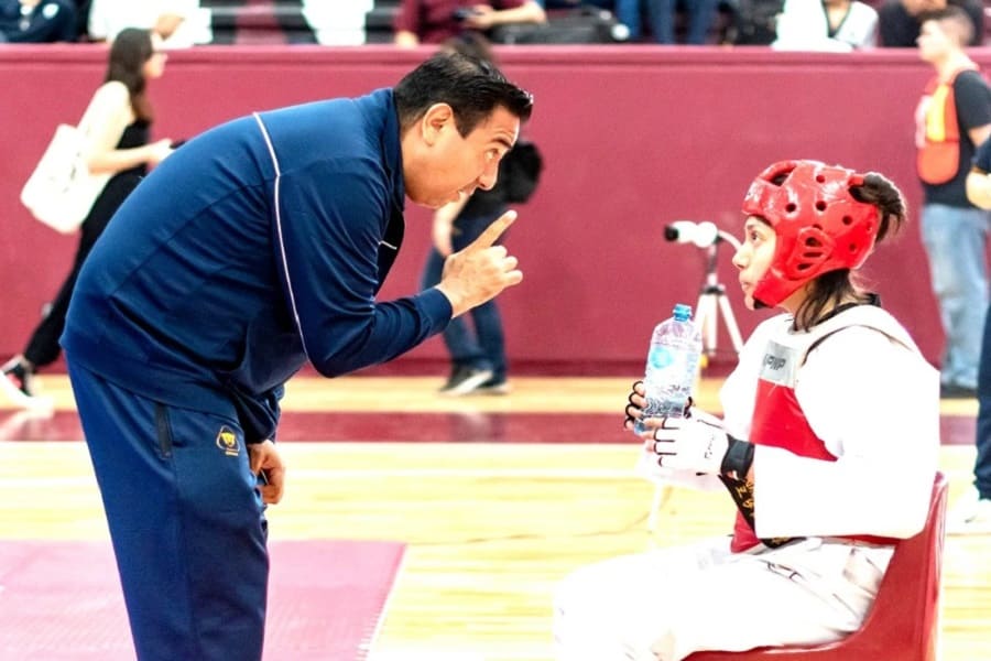 Entrenador de taekwondo platica son su atleta.