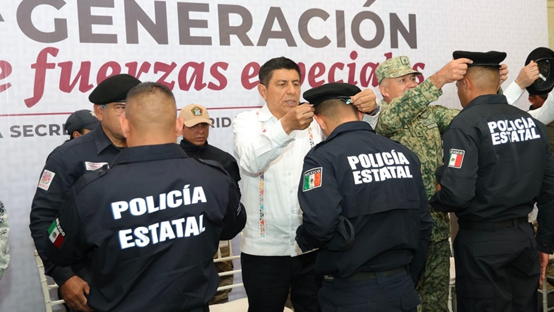 Salomón Jara coloca una boina a un elemento de fuerzas especiales de Oaxaca vestido con uniforme negro, junto a otros como él..