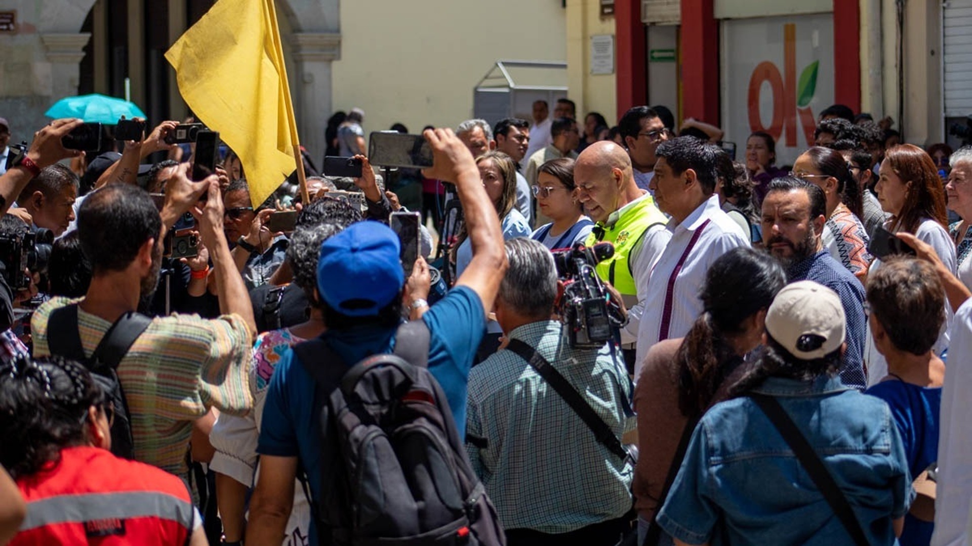 Decenas de personas reunidas en una calle; algunas sostienen teléfonos para grabar la imagen.