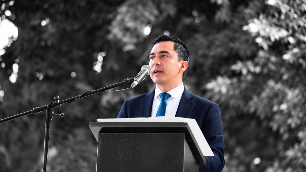 Juan Carlos Chávez Martínez con traje negro ofreciendo un discurso desde un atril