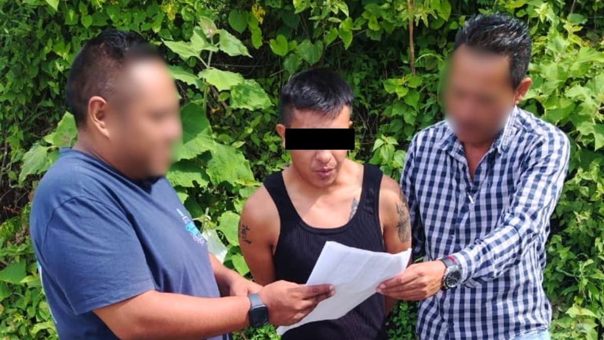 Hombre con los ojos protegidos por ley es detenido por dos personas, quienes le muestran un documento