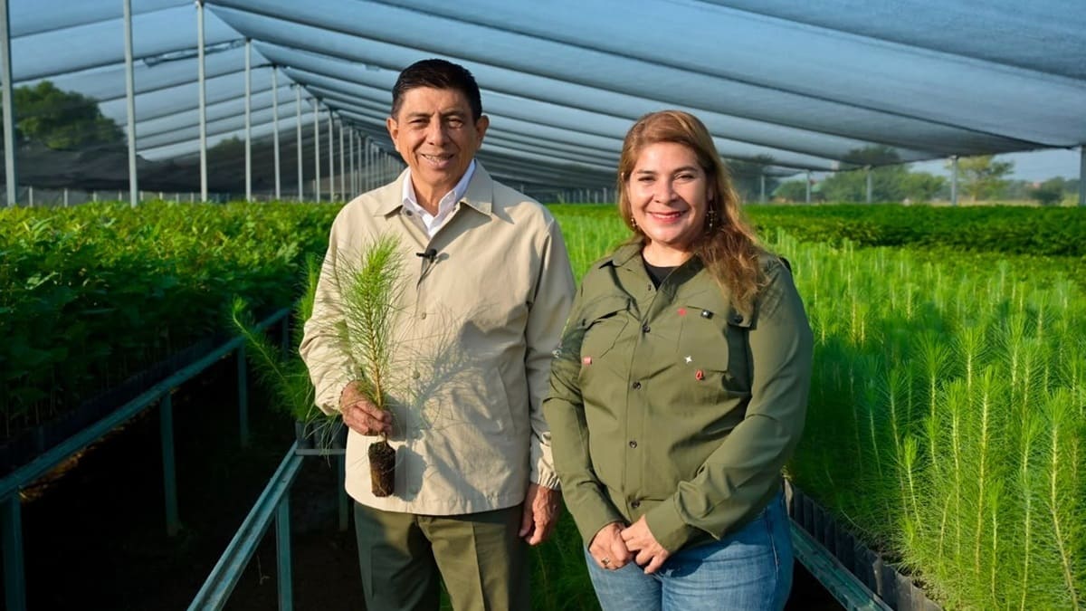 Salomón Jara Cruz sostiene una planta junto a una mujer en un vivero