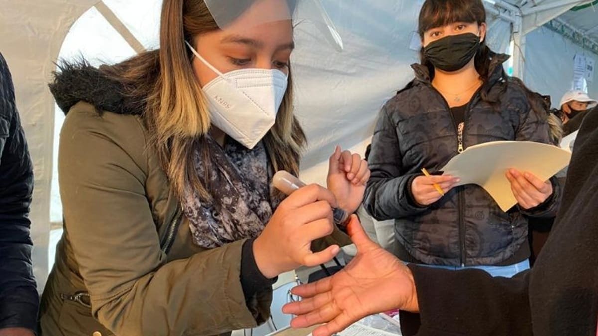 Tres mujeres con tapabocas interactúan durante una elección, una pinta el dedo a otra