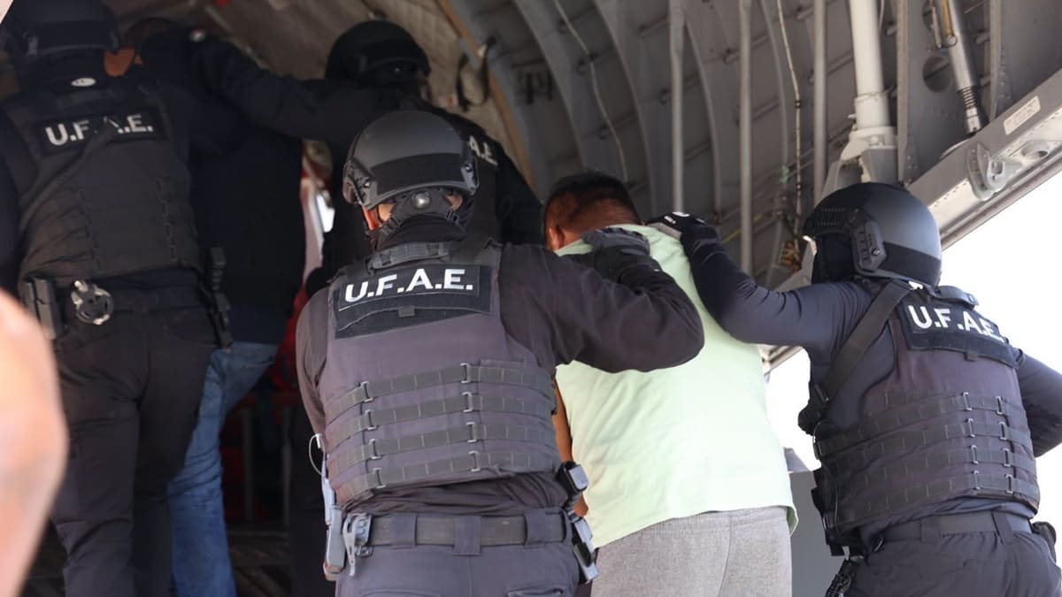 Persona detenida y custodiada por dos elementos de seguridad