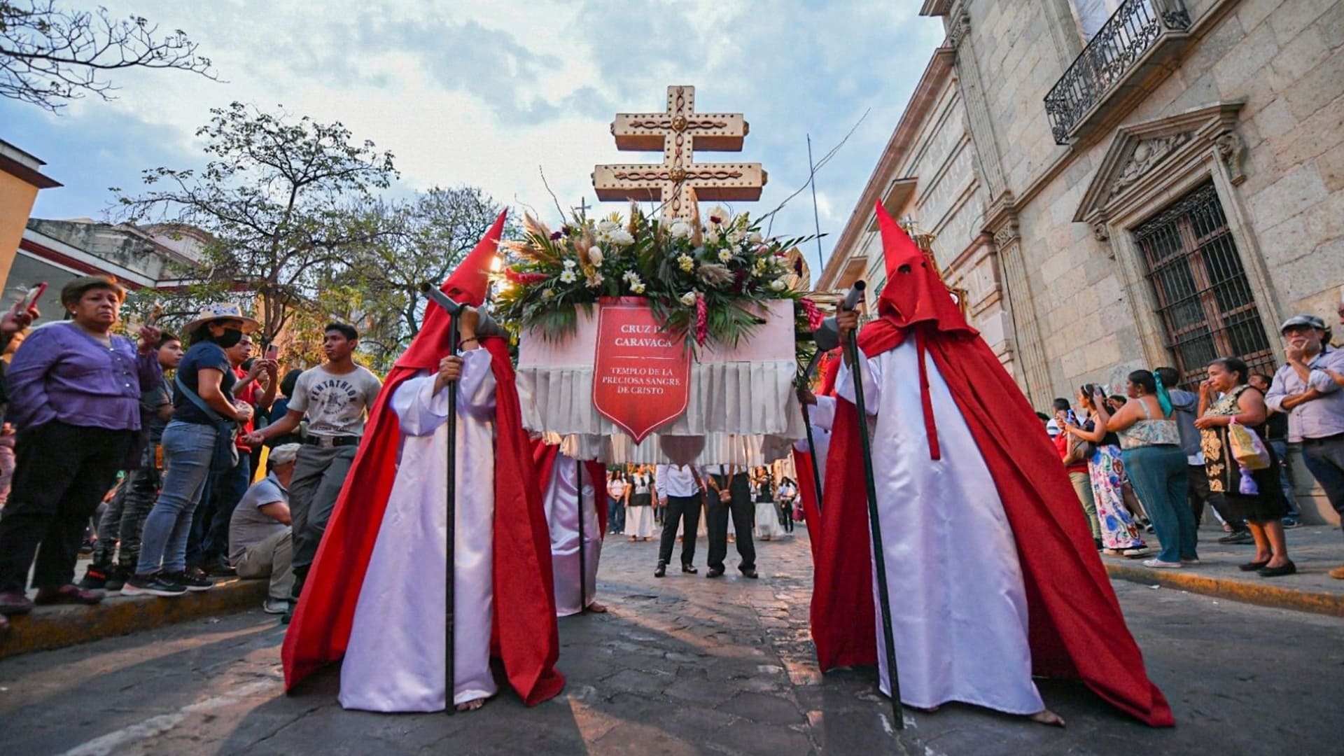 Dos personas vestidas con túnicas en colores blancy rojo, con el rostro cubierto.