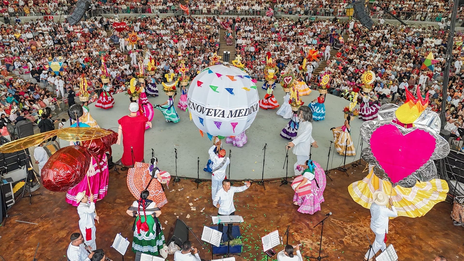 Varios bailarines, músicos y público una representación artística en el Auditorio Guelaguetza de Oaxaca.