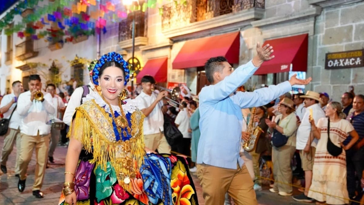 Mujer istmeña con tocado azul vestida con traje típico colorido camina por una de las calles céntricas de Oaxaca