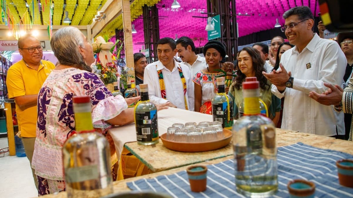 Salomón Jara visitando un stand en la Feria del Mezcal 2026, donde platica con una adulta mayor vestida con traje regional.