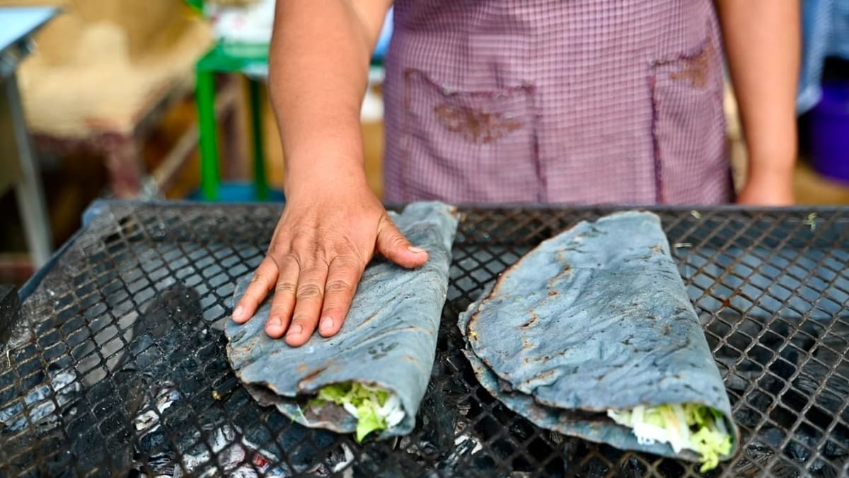 Manos adultas preparando un par de tlayudas sobre un horno