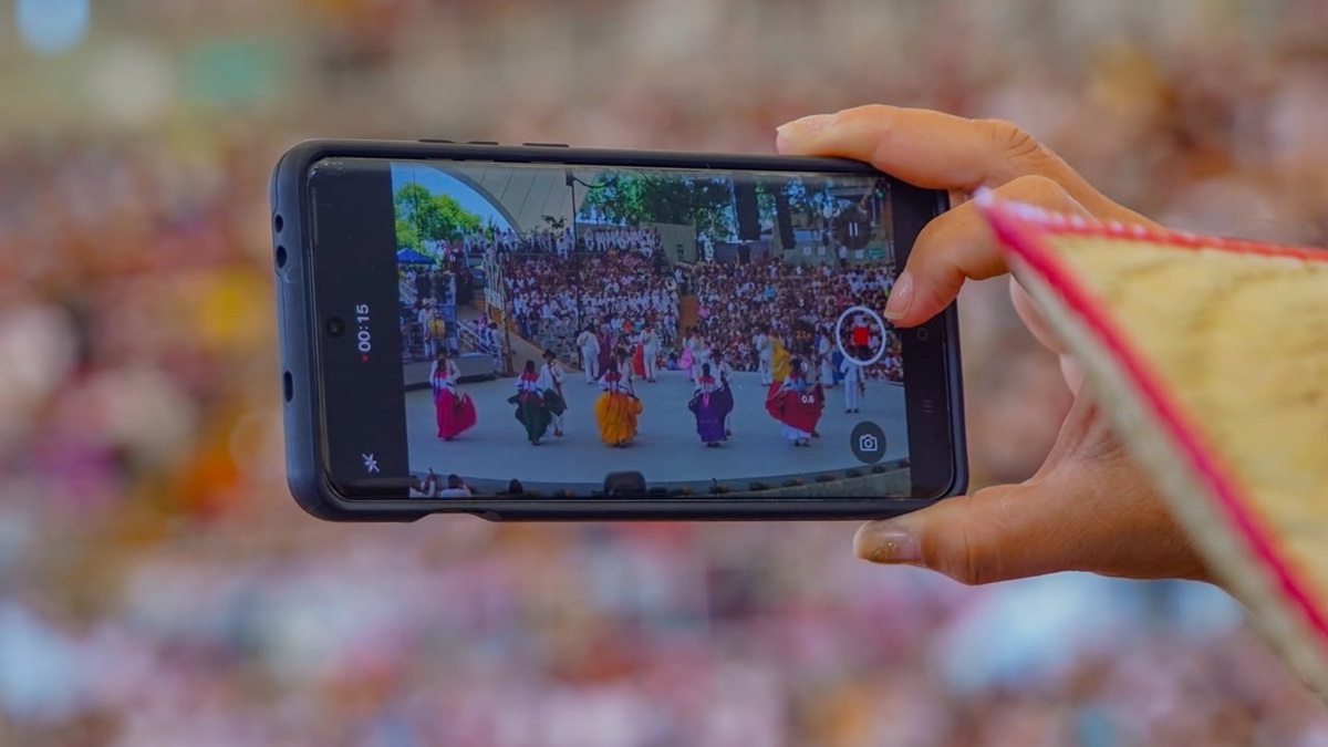 Una persona muestra su celular, con el que está tomando imágenes de la Guelaguetza 2026.