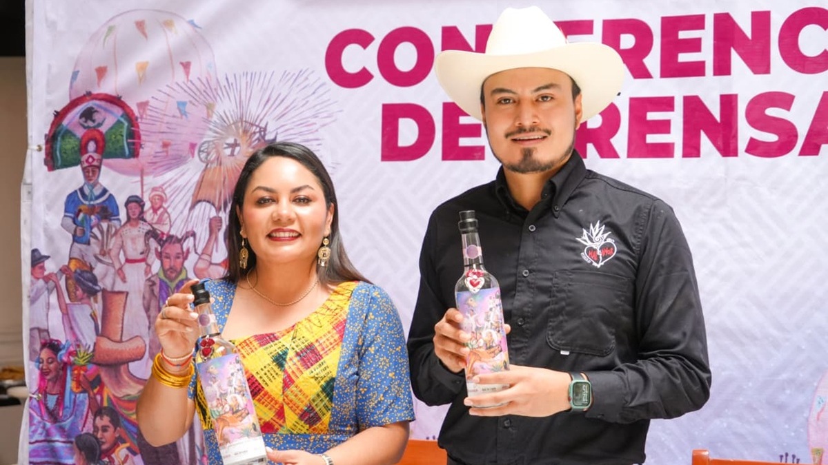 Expositores muestran la botella del mezcal conmerativo de la Guelaguetza 2026 en Oaxaca