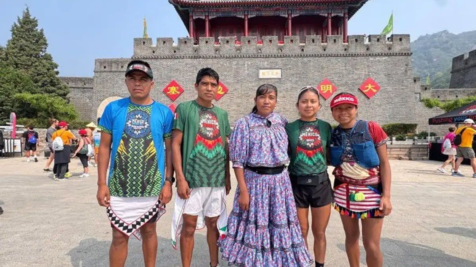 Dos hombres y tres mujeres vestidos con ropa regional mexicana, frente a un palacio estilo chino.