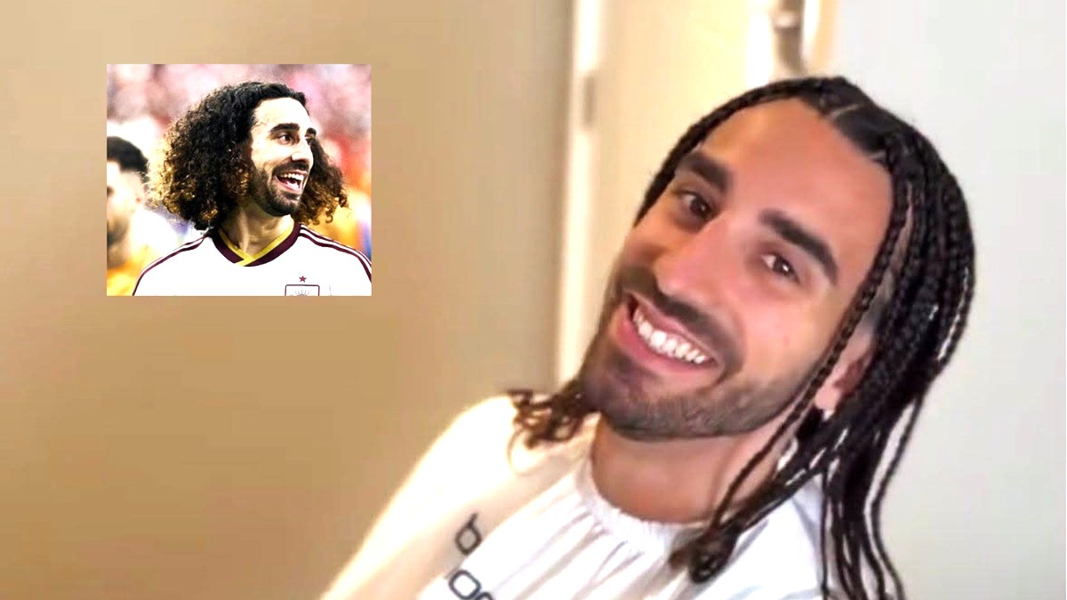 Marc Cucurella sonríe a la cámara mientras usa una bata blanca y luce trenzas en el cabello