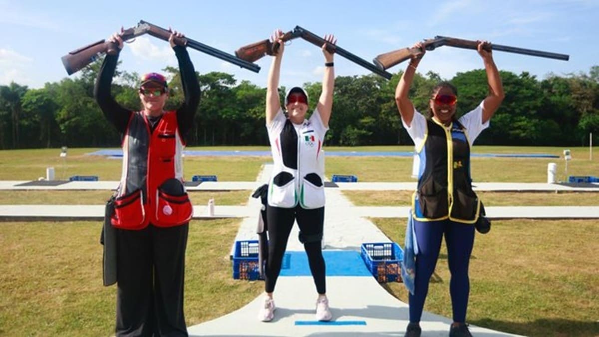 Tres atletas mexicanos de tiro deportivo uniformados y con sus rifles en lo alto