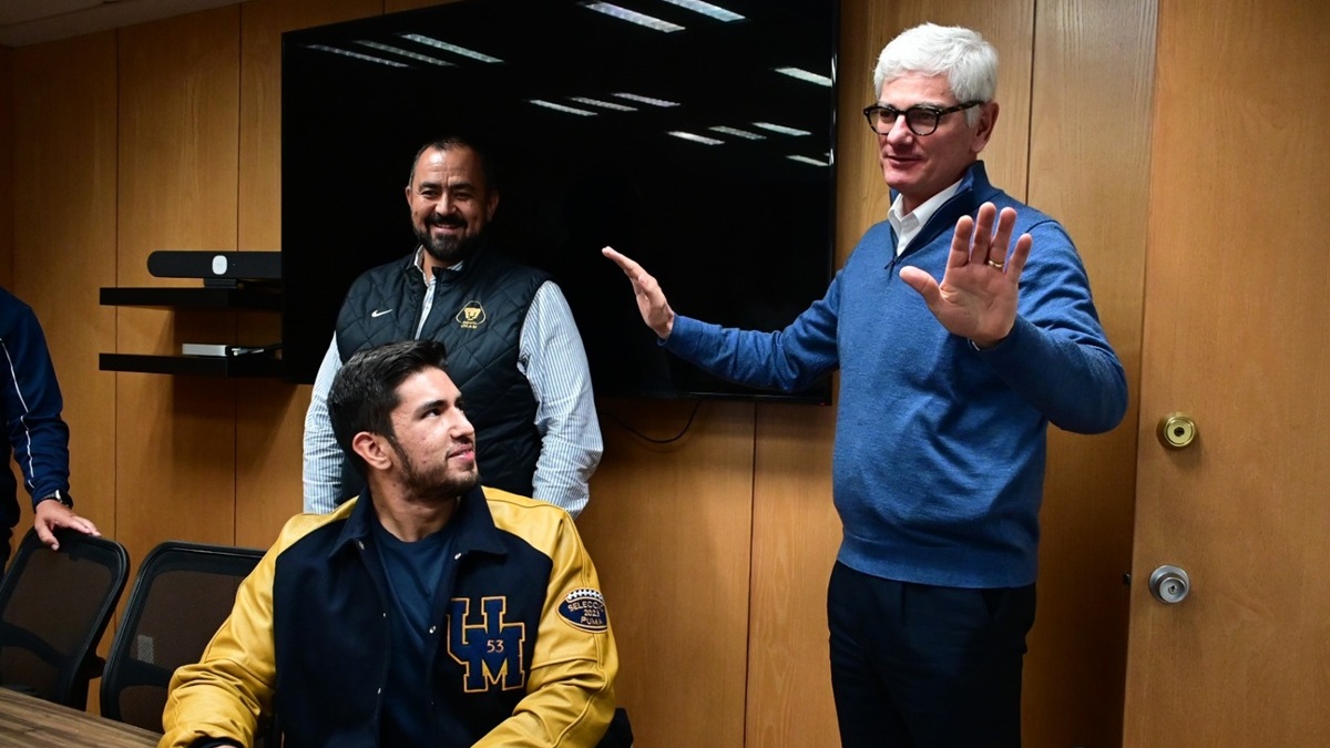 Arturo Olivé de cabello blanco, suéter azul y lentes, junto a un jugador de Pumas CU