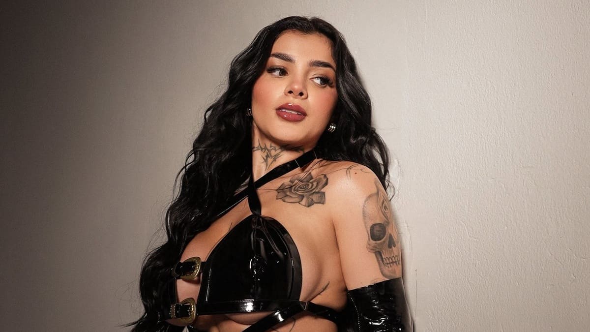 Karely Ruiz con traje negro y posición sensual en una sesión de fotos