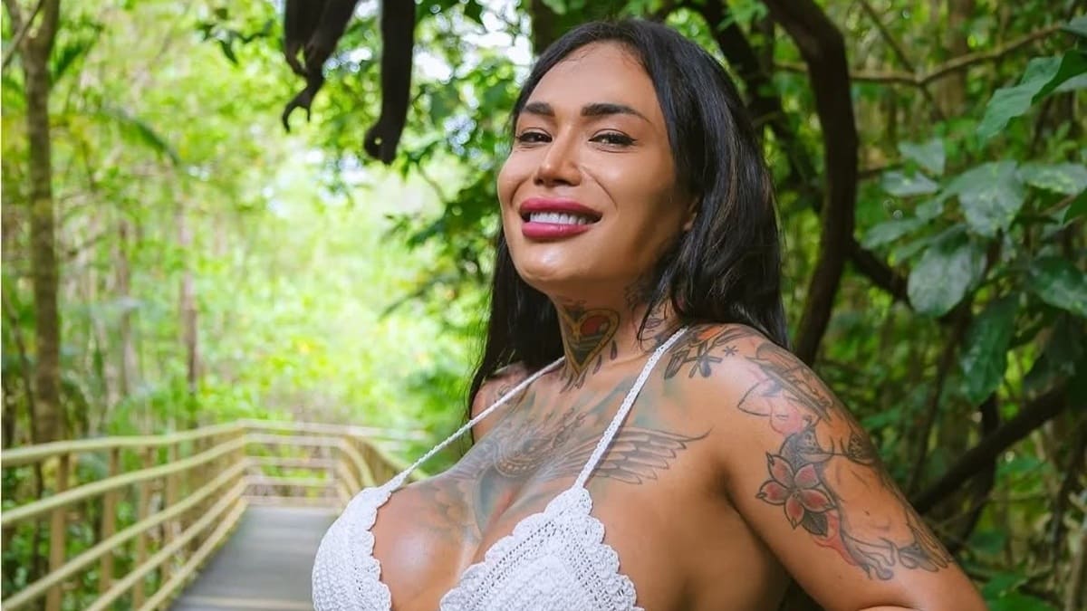 Karina Torres con traje de baño blanco, sonriente y en un ambiente selvático