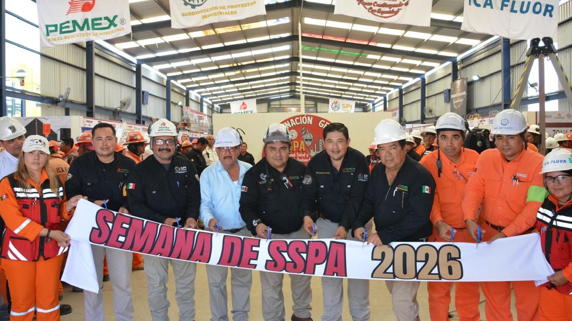 Varios trabajadores de Pemex, algunos con overol naranja y casco, posan ante la cámara.