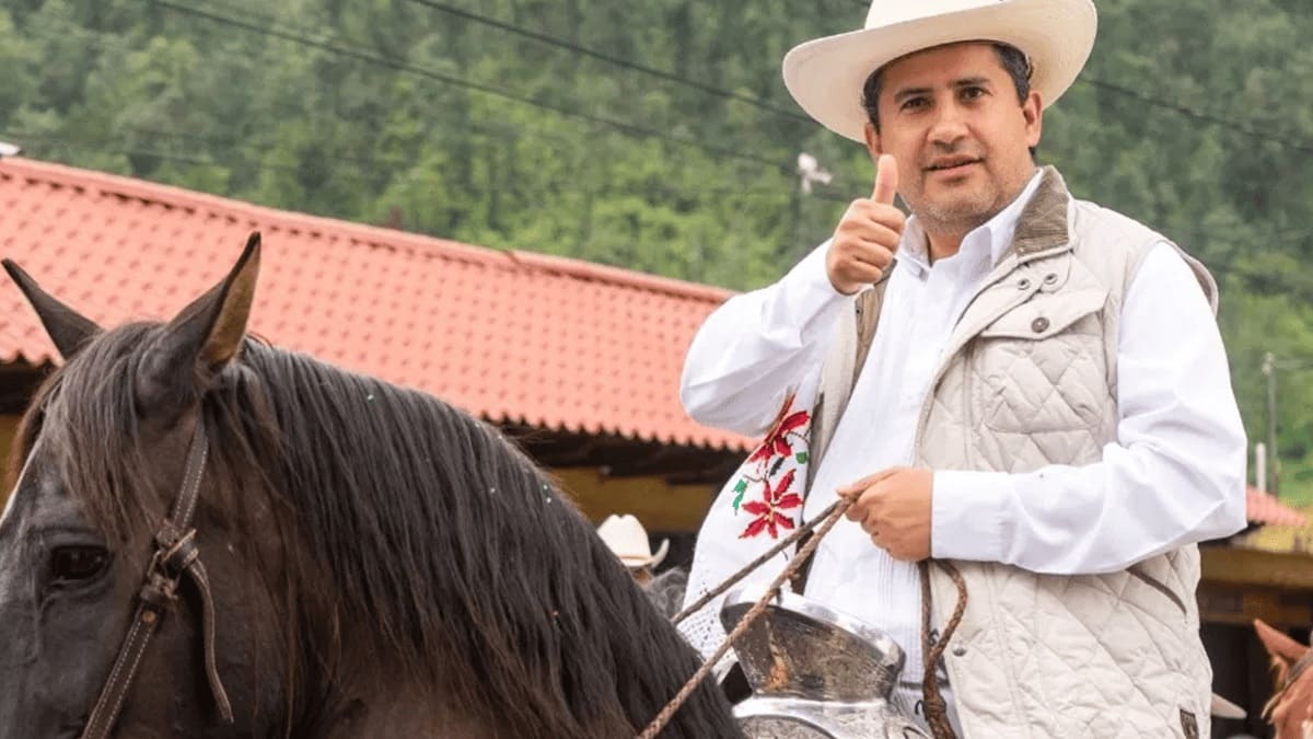 Carlos Manzo saludando con el pulgar el alto mientras monta a caballo