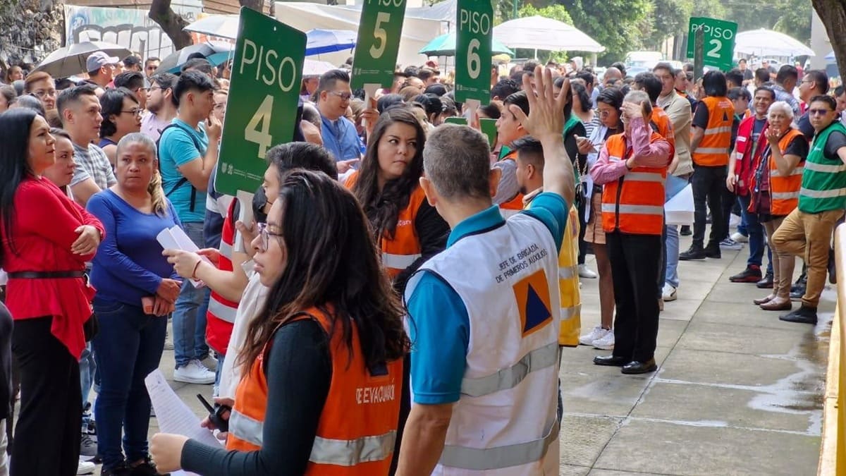 Varias personas, algunas con chaleco naranja, reunidas en un patio