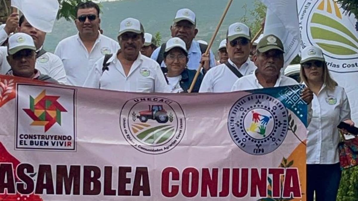 Grupo de personas, algunas con gorras, sosteniendo una manta en una calle