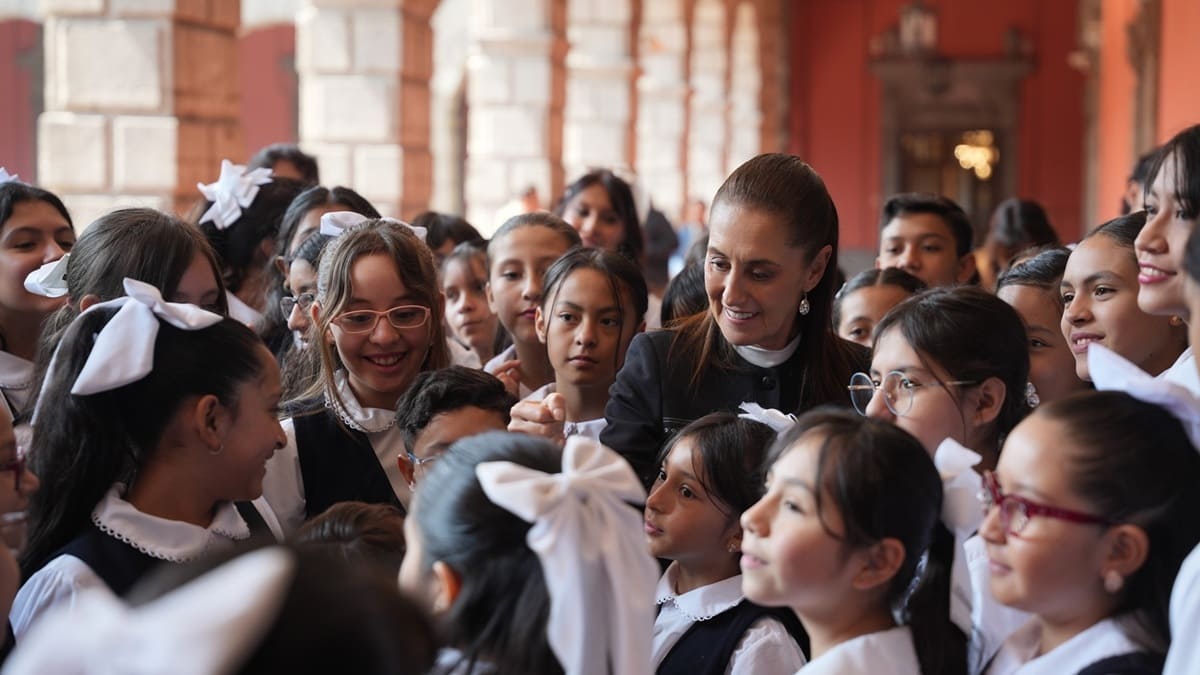 Claudia Sheinbaum entre niñas uniformadas a las que sonríe