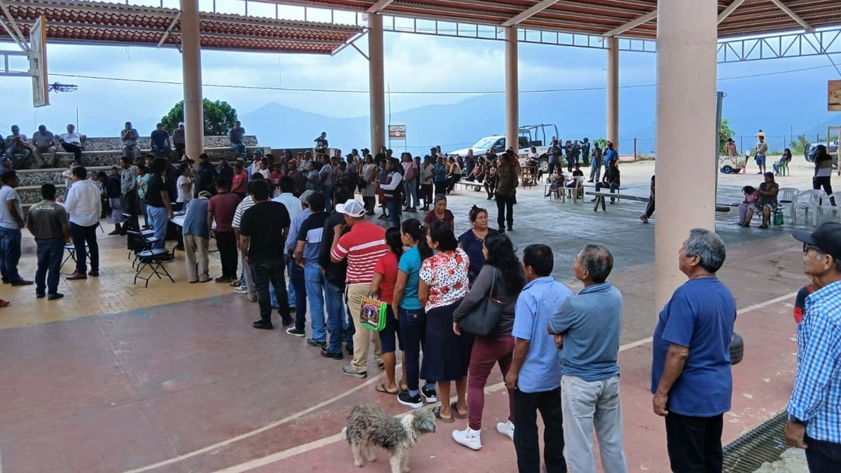 Decenas de personas con ropa casual hacen filas en una cancha techada de Santiago Xanica