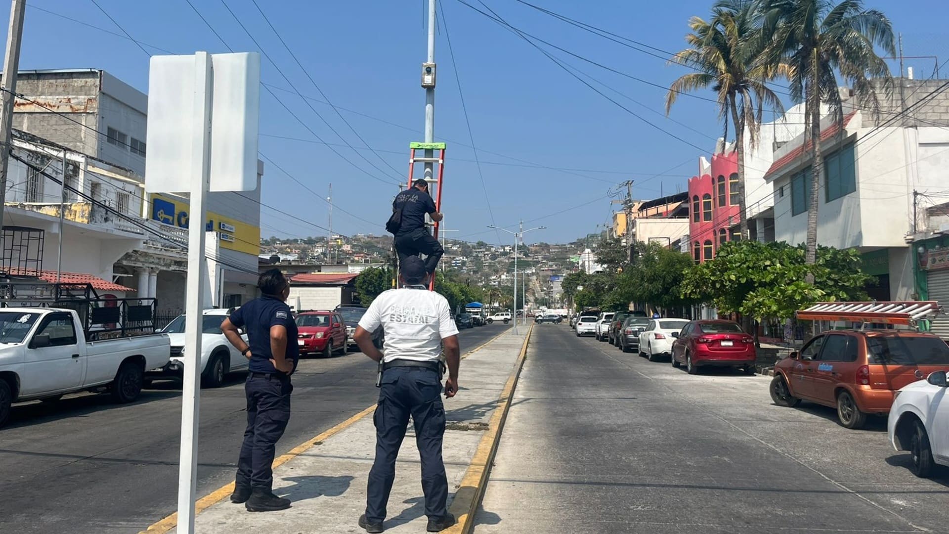 Tres policías retiran cámaras de videovigilancia en una calle de Salina Cruz, en Oaxaca.