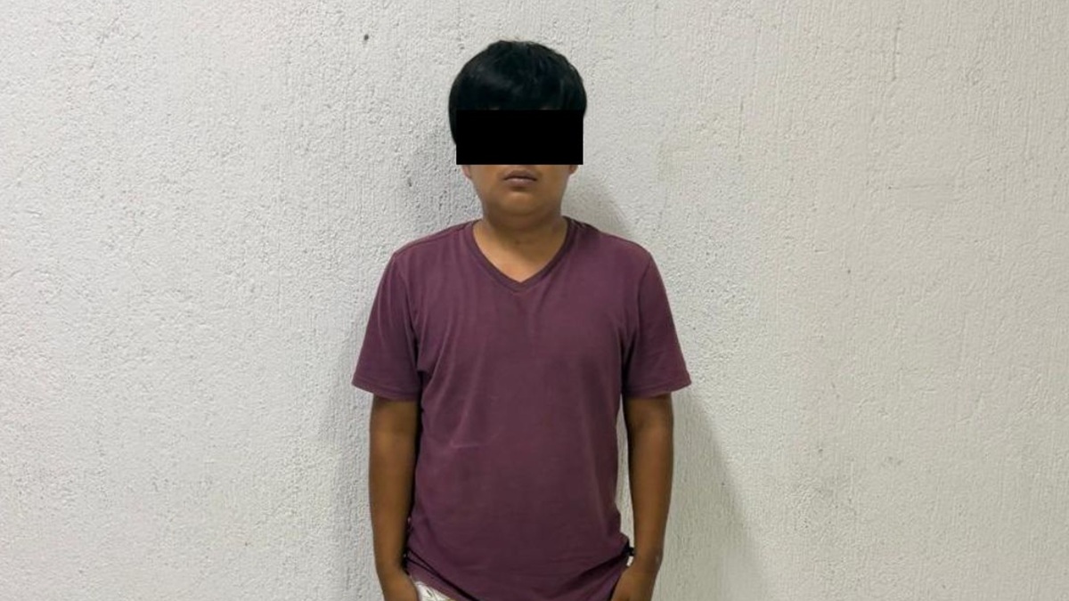 Persona detenida como playera roja y rostro cubierto por mandato de ley