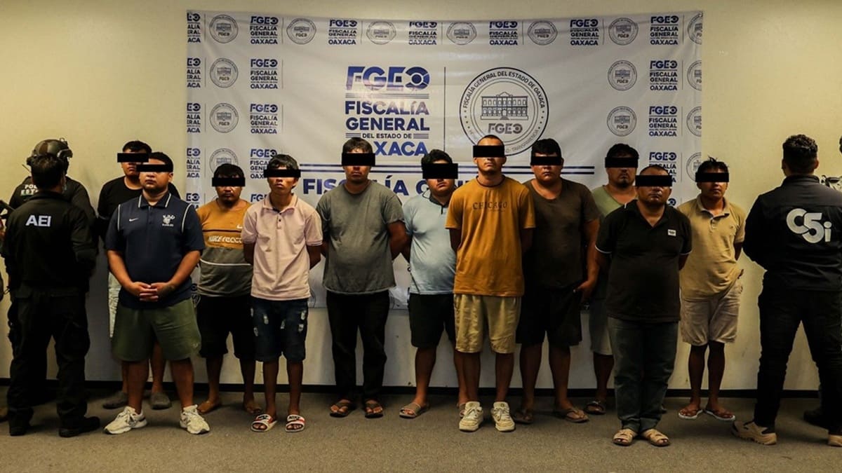 Varias personas se muestran contra una pared con los ojos cubiertos con franja negra y custodiados por agentes