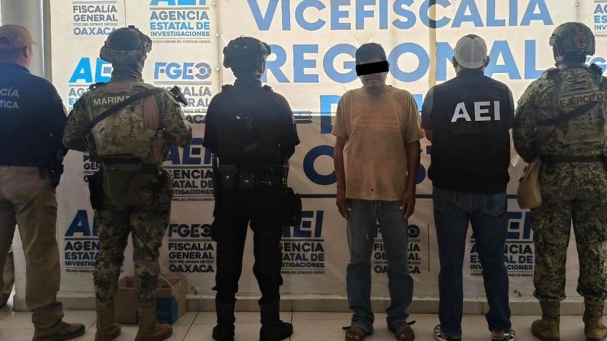 Un hombre con el rostro cubierto por ley, custodiado por cinco agentes de corporaciones de seguridad
