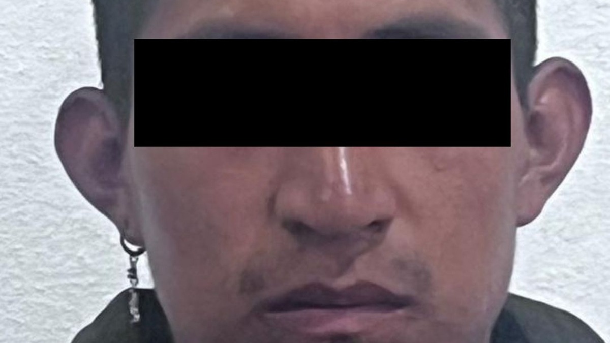 Un hombre con el rostro cubierto por ley, custodiado por cinco agentes de corporaciones de seguridad