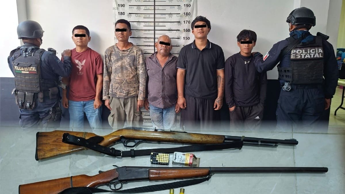 Cinco personas detenidas y exhibidas contra un muro con ropa casual y los ojos protegios, entre dos elementos de la policía estatal 
