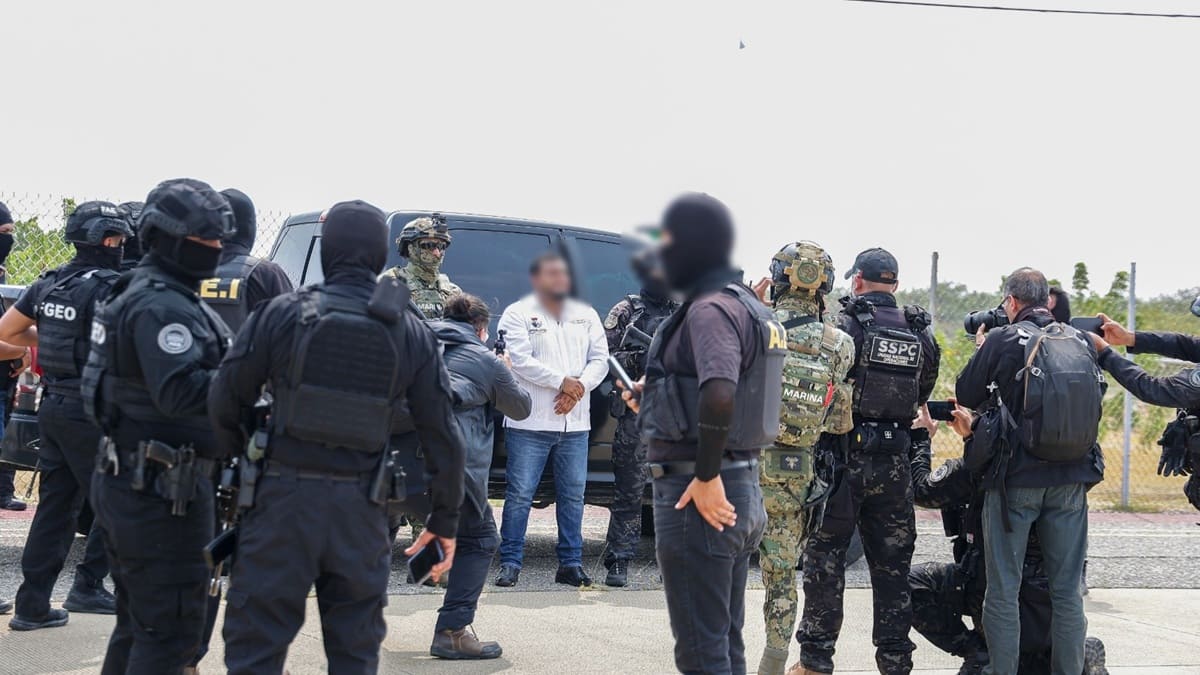 Miguel Sánchez Altamirano con esposas en las manos y rodeado de elementos de seguridad pública