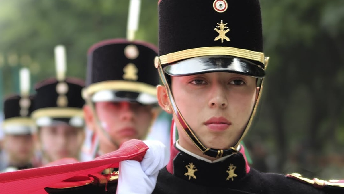 Una mujer del Ejército Mexicano con uniforme saluda de mano a un mando durante una ceremonia