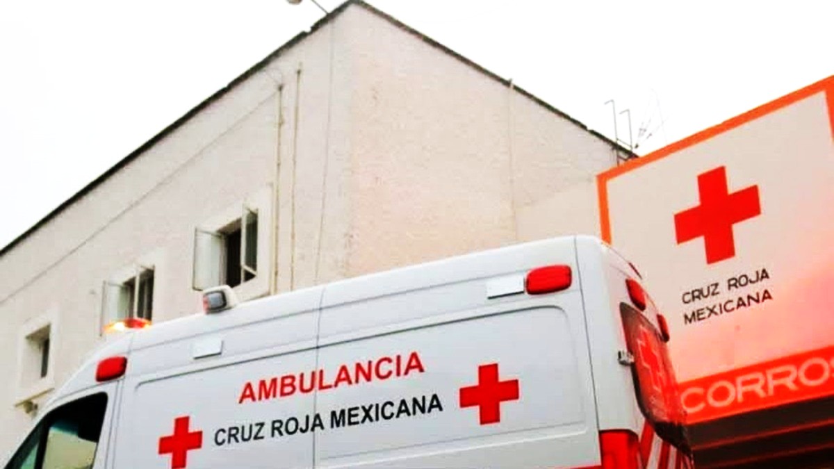 Ambulancia con logos de la Cruz Roja frente a un edificio también con logos de la misma institución en color rojo