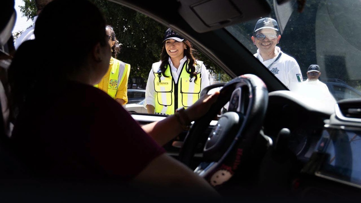 Imagen de un conductor sosteniendo un volante mientras observa por la ventanilla a personas son chalecos amarillo