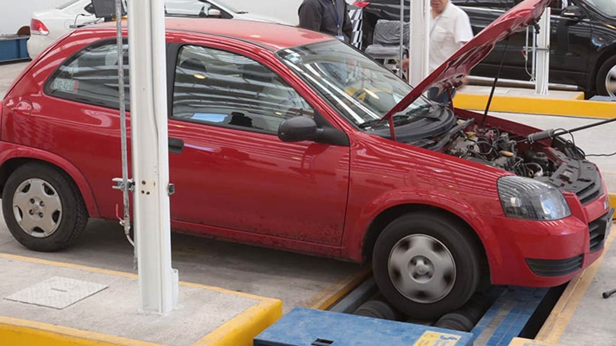 Auto compacto rojo estacionado en un centro de verificación, donde es inspreccionado
